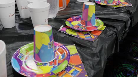 b-day party for kids with happy birthday plates cups and napkins on public event space table with pitchers of soda and children’s names on cups - in cinema 4k (30fps slowed from 60fps).