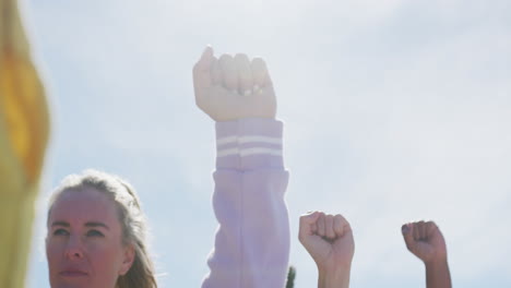 diverse group of female friends raising fists at the beach