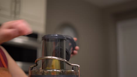 Woman-putting-variety-of-different-fruits-into-top-of-electric-juicer-to-make-healthy-fresh-fruit-juice---female-caucasian-hand-putting-sliced-fruits-in-juicer-electric-kitchen-appliance-close-up