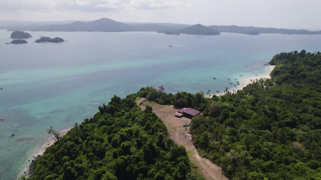 Aerial View of a Lush Tropical Island Coastline with Turquoise Waters and Distant Islands