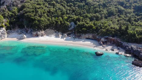 Paradiesstrand-Mit-Weißem-Sand,-Gesäumt-Von-Felsen-Und-Ruhigem,-Kristallklarem,-Türkisfarbenem-Meerwasser