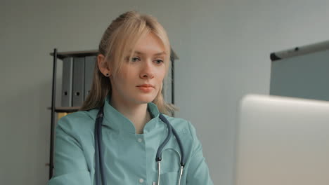 Portrait-Of-Young-Pretty-Blonde-Female-Nurse-Care-Taker-Using-A-Computer