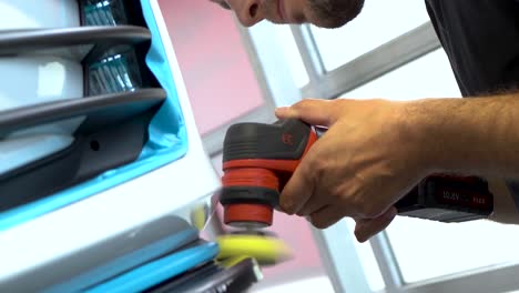male person who is using a small polishing machine to polish some small details , parts of a car. a working person. only the hands are visible of the person. this clip was shot in uhd.