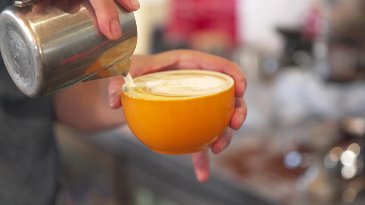 Barista che versa il latte nel caffè creando latte art in tazza.