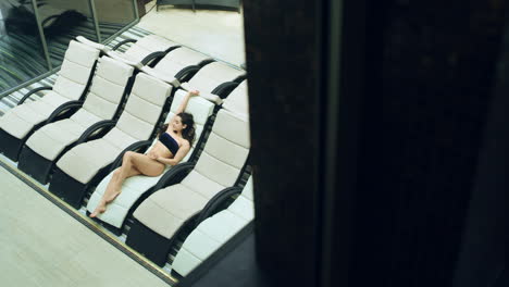 through window view of pretty girl lying on deckchair in spa