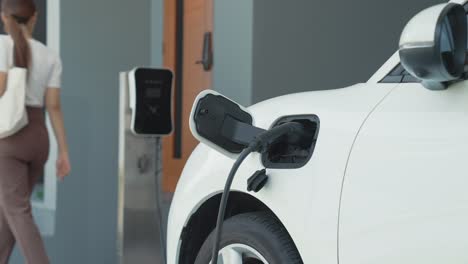 progressive woman unplugs the electric vehicle's charger at his residence.