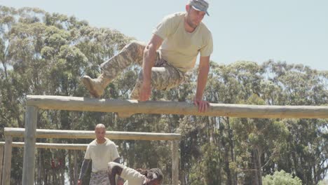 grupo diverso de soldados varones pasando por encima y debajo de obstáculos en el curso de obstáculos del ejército en el campo
