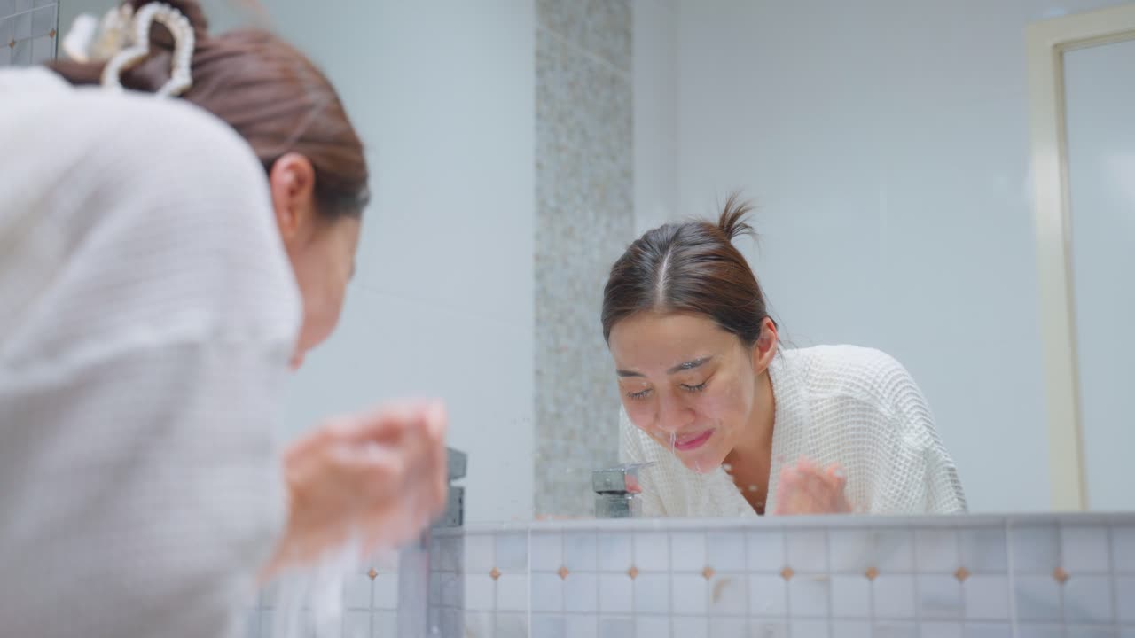 mujer lavándose la cara en el baño