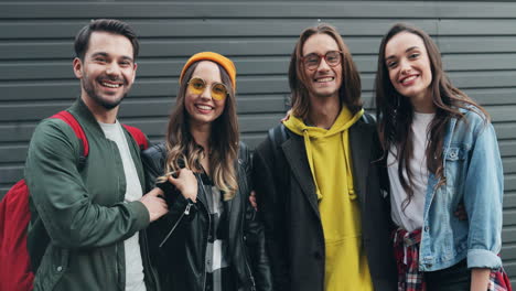 Portrait-shot-of-caucasian-young-group-of-friends-posing-on-a-wall-and-smiling-to-the-camera-in-the-street