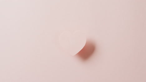 코피 스페이스와 함께 희미한 분홍색 배경에 상승 된 분홍색 심장과 그림자의 오버헤드 비디오