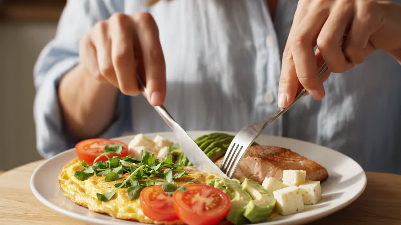 Person enjoying a healthy meal with salmon, omelet, and fresh vegetables