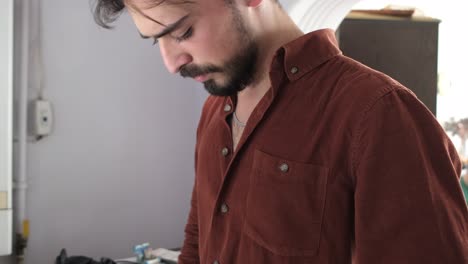 young man getting dressed and looking good, guy straightening his shirt collar in front of a public mirror