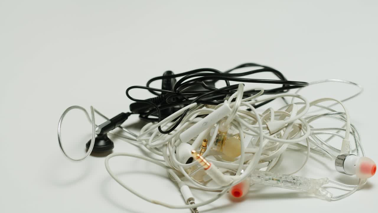 Untangle the headphones close-up. Tangled wires on table. Trying to untangle many messy cables