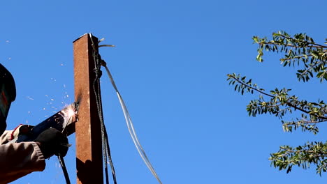 tradesman welding steel support poles outdoors ensuring safety standards
