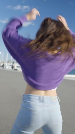 energetic young woman dancing outdoors by a marina
