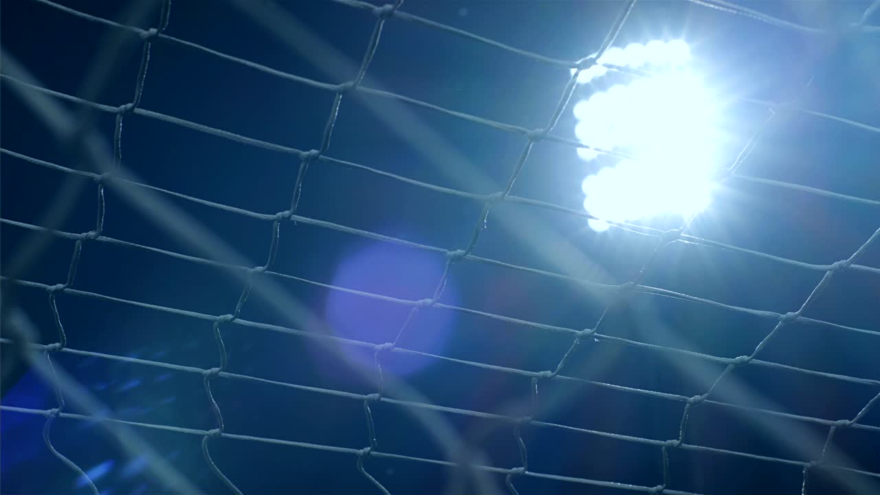 Karanlık gökyüzüne karşı futbol/spor stadyumu ışıklarının arka planı, önünde ağ ile, 4k