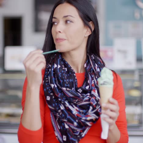 mujer joven sonriente saboreando un cono de helado
