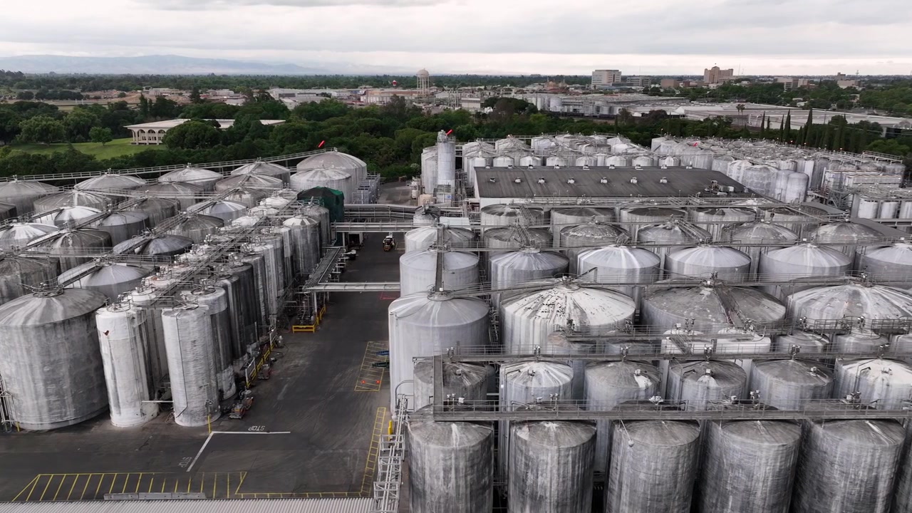 Industrieanlage der Gallo Weinkellerei in Modesto, Kalifornien, mit ausgedehnten Reihen von Edelstahltanks und Produktionsgebäuden. Groß angelegte Weinproduktionsabläufe. Seitliche Weitwinkel-Luftaufnahme.