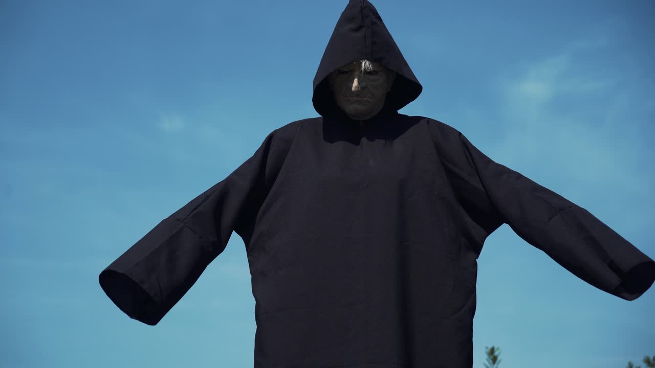 Eerie witch watches the camera. Halloween costume.