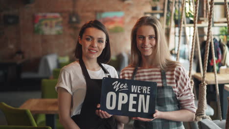 two women greet customers at a cafe
