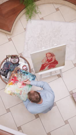 man creates portrait of lady in red in home studio. skilled portraitist combines colors on palette against lady sitting in gallery. artwork creating process