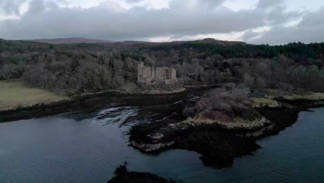 el castillo de dunvegan en la isla de skye rodeado de bosques y agua al anochecer, vista aérea