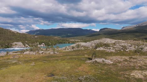 aerial picturesque view of a mountain landscape with a calm river flowing through, under a serene blue sky and scattered clouds