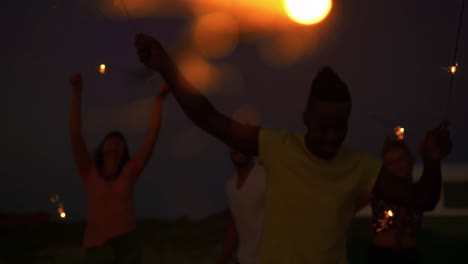 young adult friends having fun on the beach at night with sparklers 4k