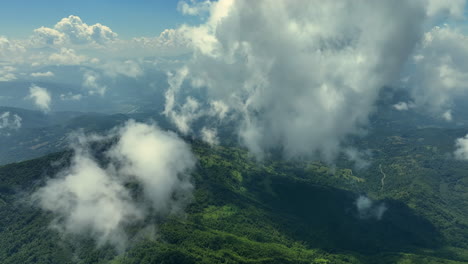 flying trough white fluffy clouds above green mountain peaks