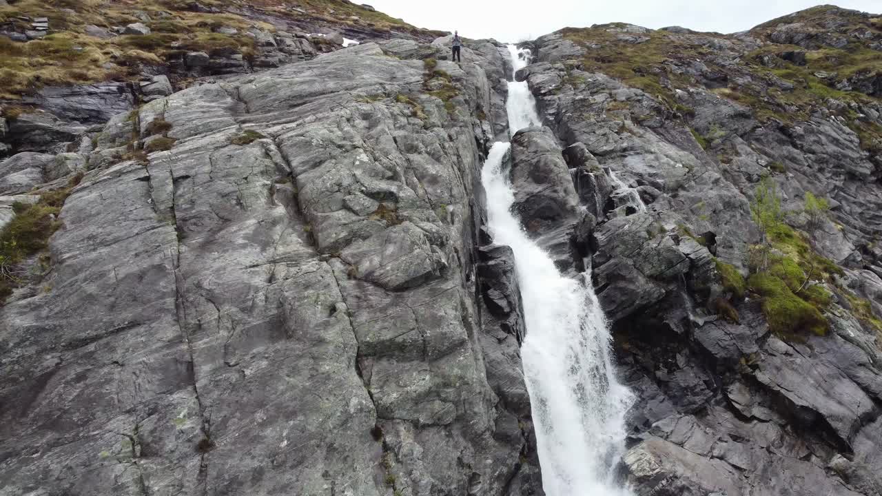 hombre volando un dron desde un acantilado escarpado con