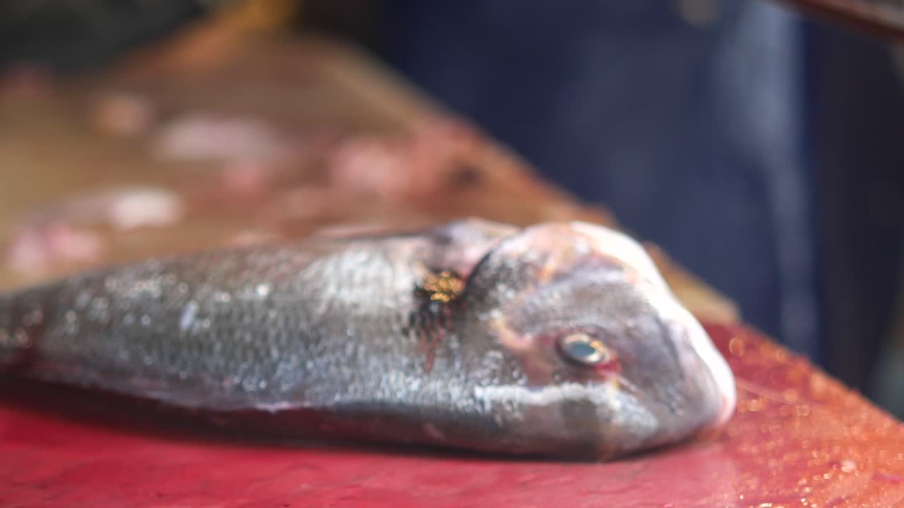 pescador limpiando un pescado fresco en el mercado