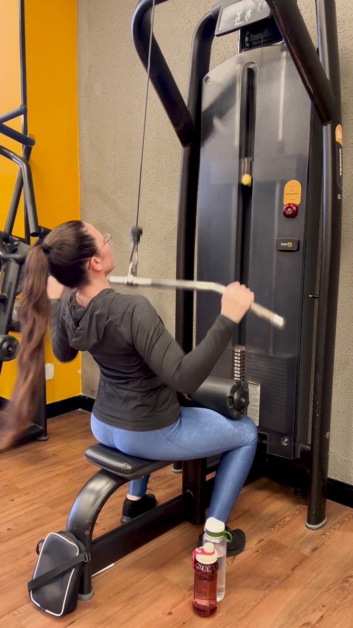 Woman performs seated cable row on weight machine, gym, fitness, muscle building and workout.