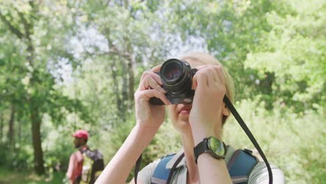 Happy-diverse-couple-with-backpacks-taking-photos-in-park,-slow-motion