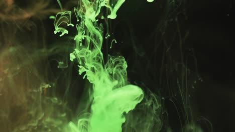 slow motion video of green watercolor ink mixing in water against black background