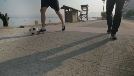 two men dribbling soccer ball on the footwalk