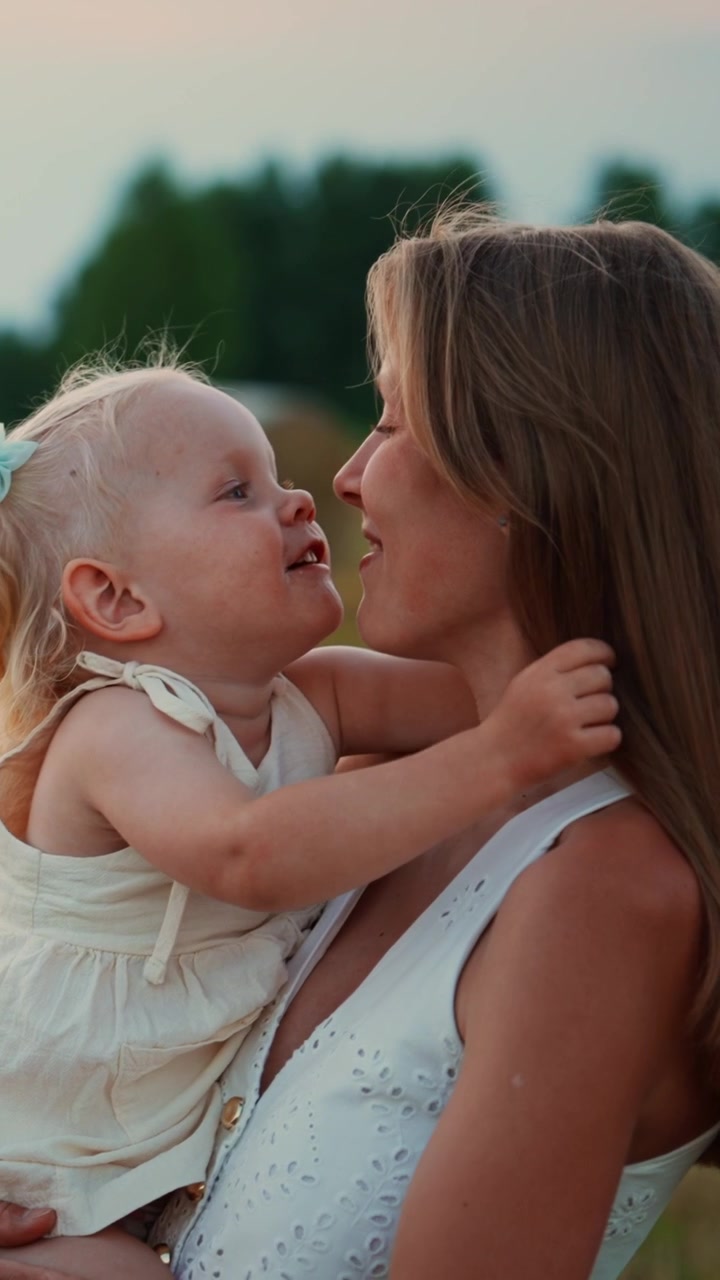 Mãe Feliz Segurando a Filha Pequena em um Campo