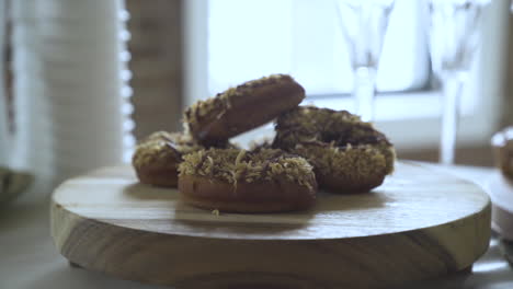 appetising chocolate donuts with sprinkles stacked on wooden board