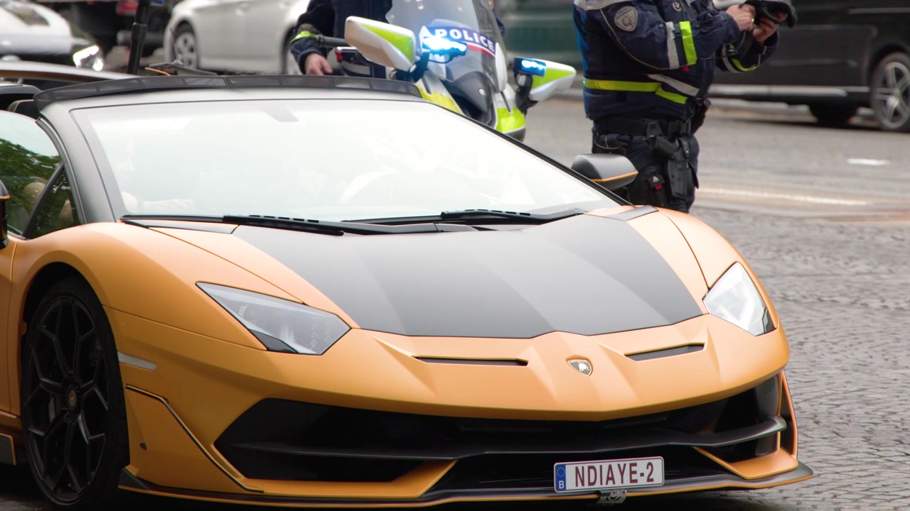 Agenti di polizia in uniforme esaminano un'auto sportiva gialla di lusso su una strada parigina.