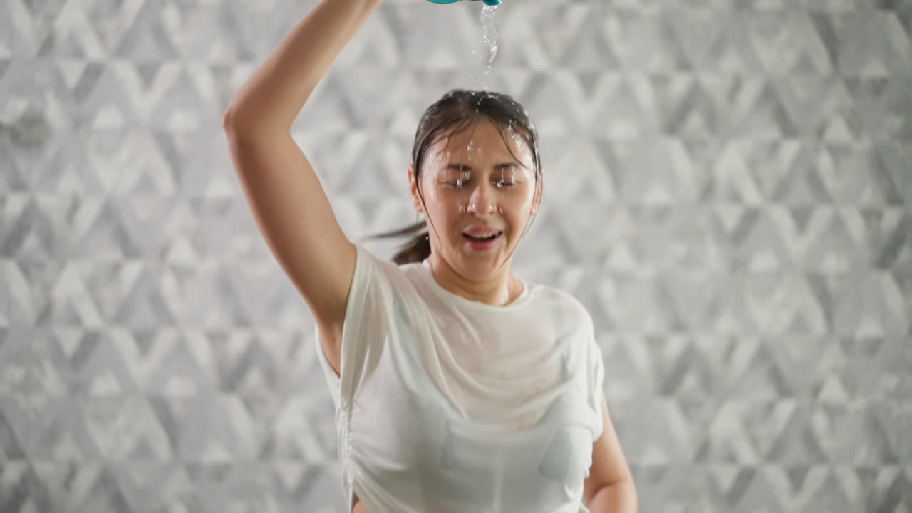 여성은 머리 위에 물을 부어 냉각합니다. 행복한 여성은 과열을 관리하여 최적의 성능을 유지합니다. 트레드밀 운동 중에 피로와 싸니다.