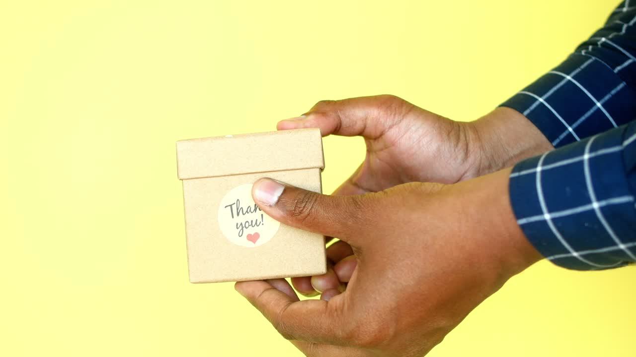 Hand holding a small thank you gift box