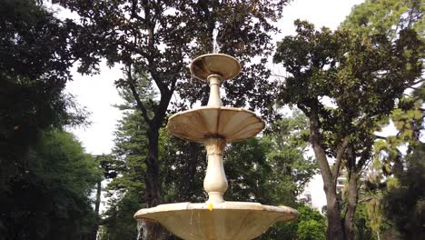 marble fountain water falling slow below tree tops green dark skyline italian sculpture panoramic view at natural environment, drops flow