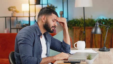 cansado agotado ocupado realizando múltiples tareas hombre de negocios indio trabajando en una computadora portátil se siente triste aburrido en la oficina
