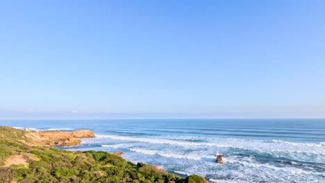 Waves crash against rocky shores under clear blue skies at Mornington Peninsula, captured in bright daylight