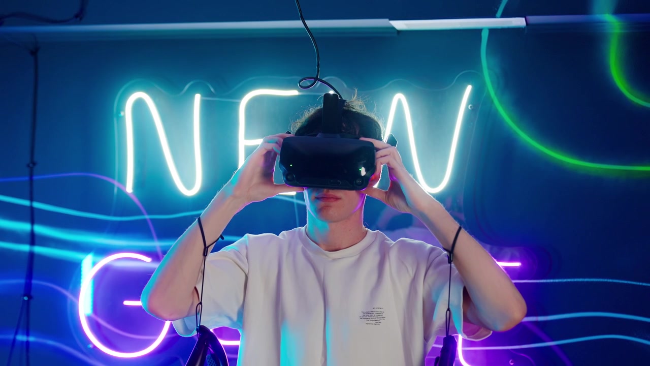 Giovane uomo indossa un visore per realtà virtuale in una stanza illuminata al neon