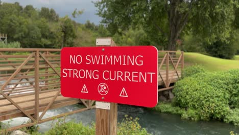 no-swimming---strong-current-sign-in-front-of-fast-moving-water-under-a-bridge-4k-30fps