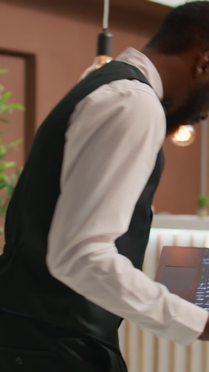 Video verticale: dipendente di hotel concentrato sul laptop