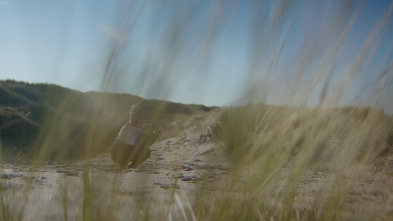 Woman Takes Pictures in Sandy Dunes - Blurred Harram Grass Foreground