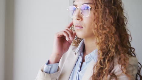 Portrait-of-smiling-biracial-businesswoman-taking-glasses-off-in-modern-office