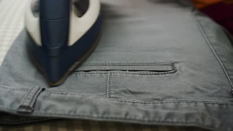 closeup of a woman ironing clothing by stream iron on board at home
