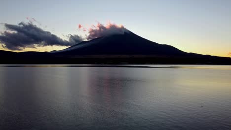 dawn breaks over a serene lake with mount fuji silhouetted against a vibrant sky